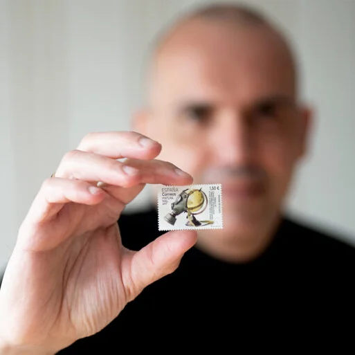 Photographer Garcia de Marina holding a postage stamp featuring one of his images